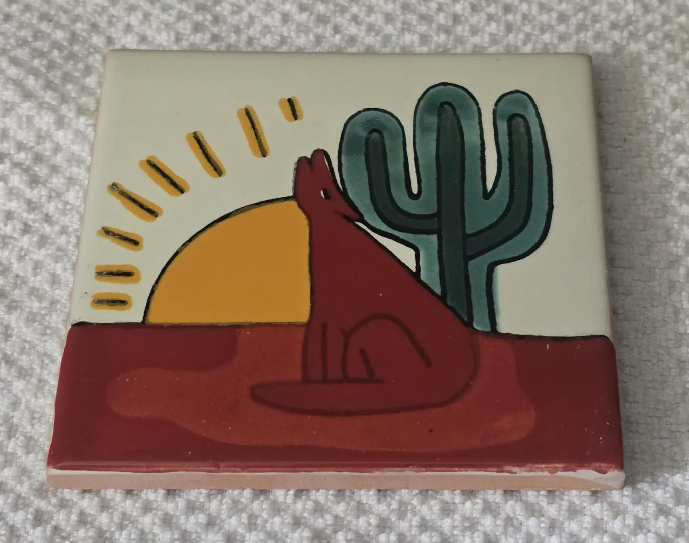 A red coyote howling at the sun near a cactus.