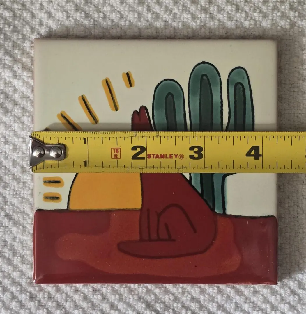 A colorful ceramic tile with an abstract hand design and a measuring tape.