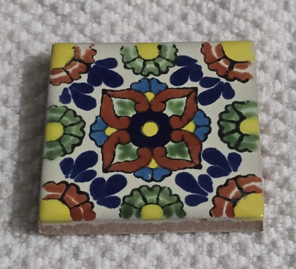 Colorful floral ceramic tile on white towel
