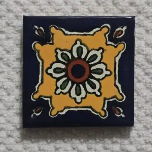 Decorative ceramic tile with floral and geometric design in yellow, black, white, and red.