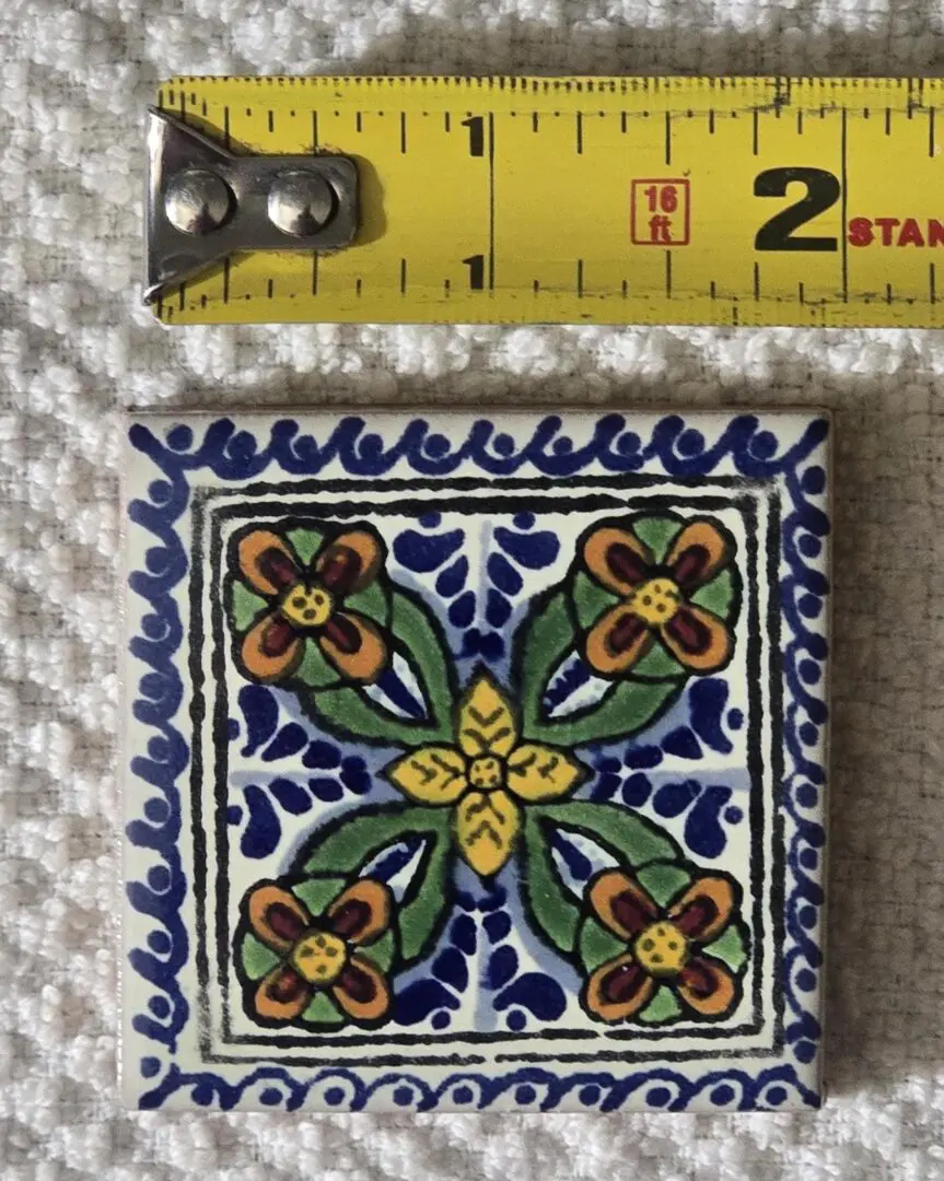 Decorative tile with floral pattern beside ruler.