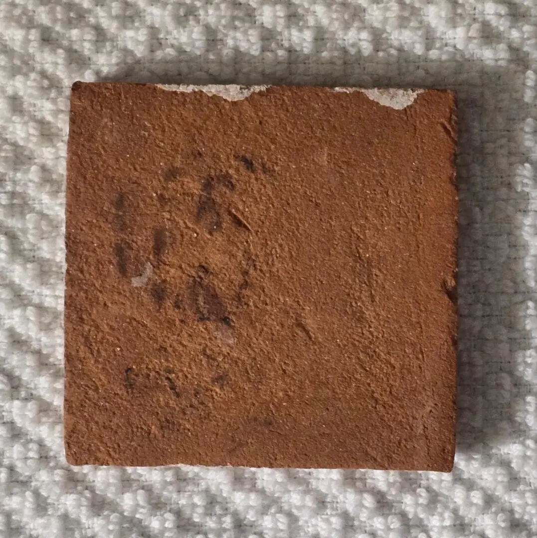 Worn square terracotta tile on white towel