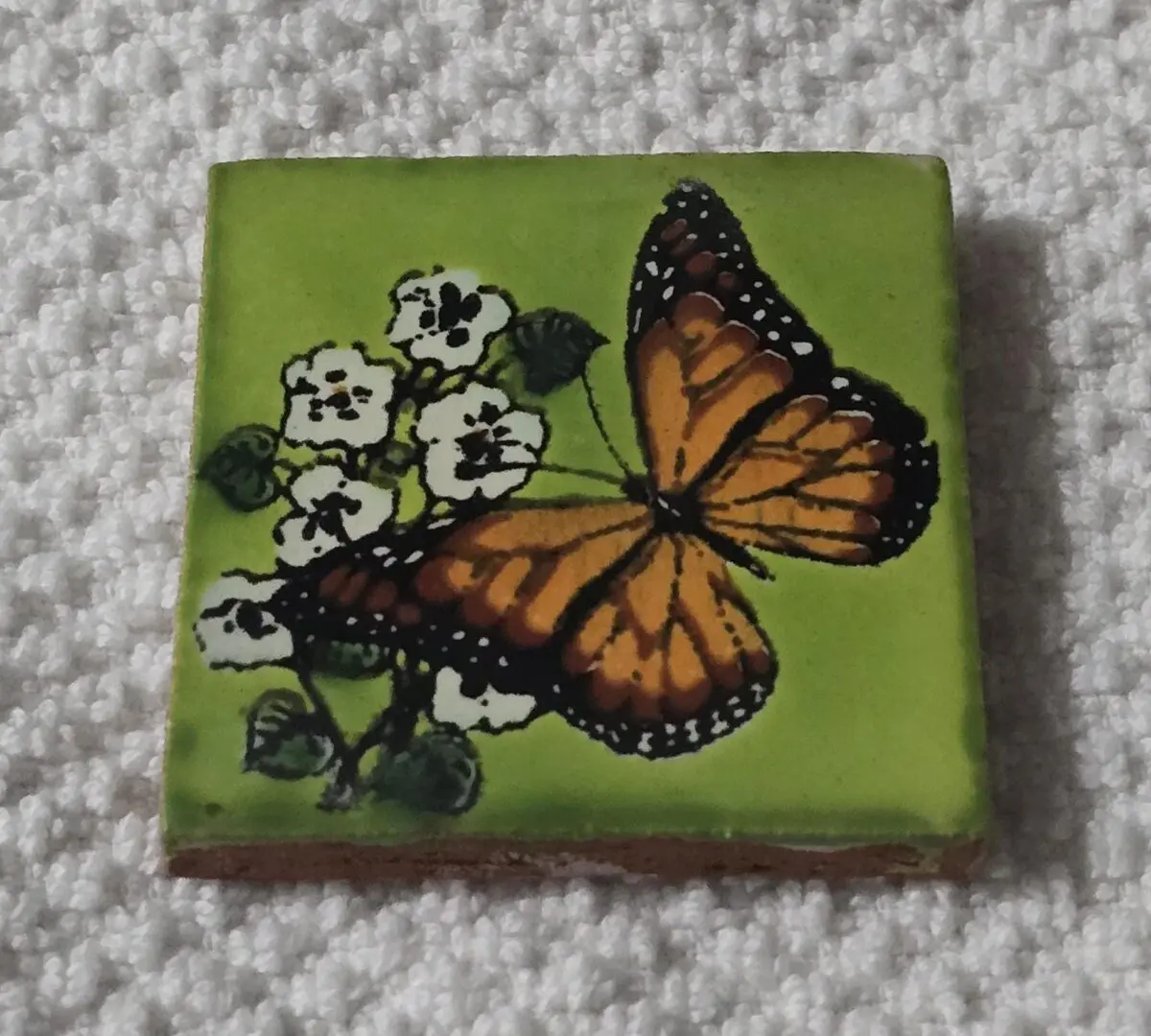 A butterfly on a green floral tile.