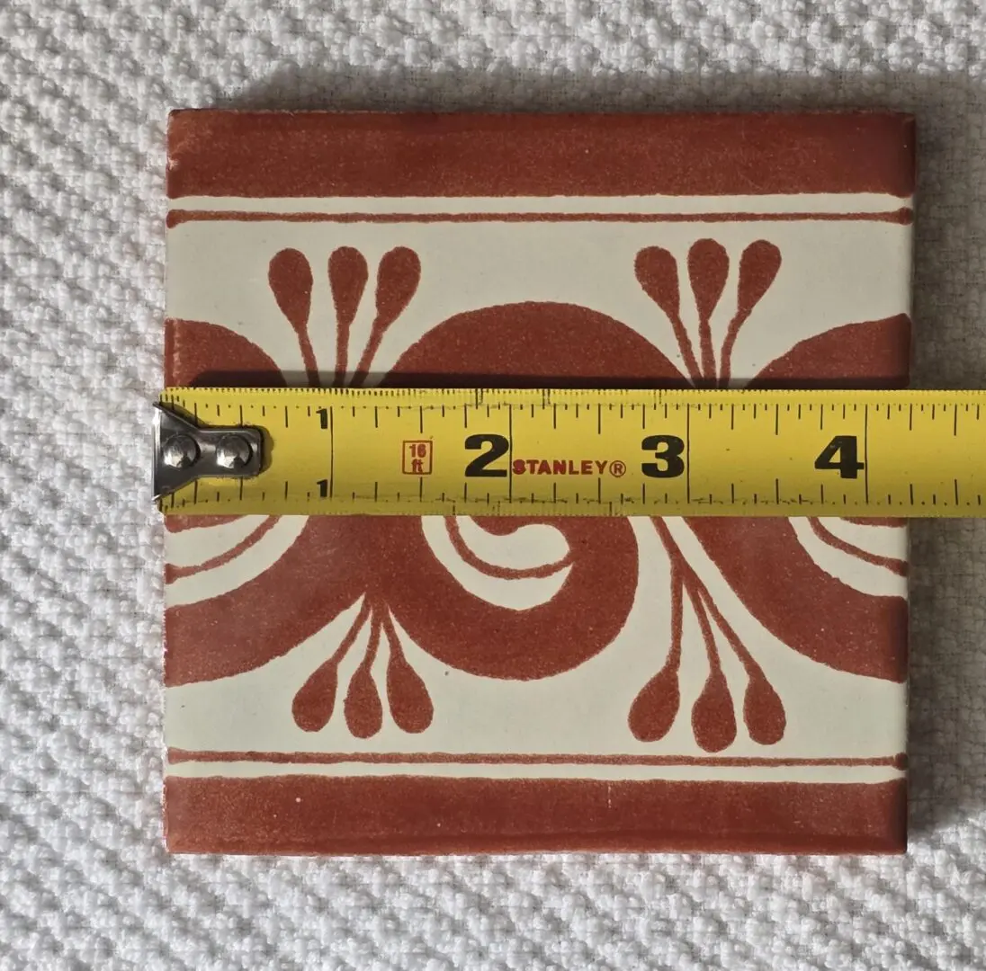Red floral ceramic tile with measuring tape