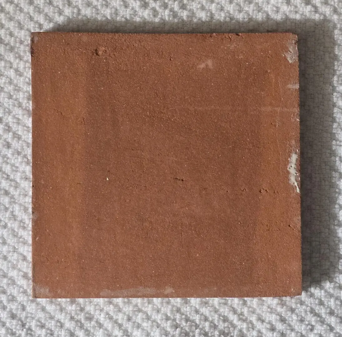 Red brick tile on textured white surface.