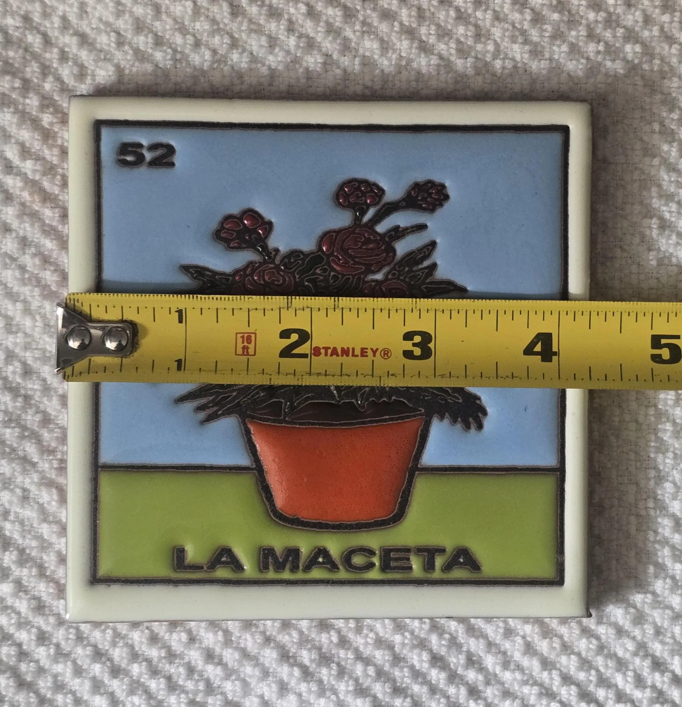 Tile with potted plant and measuring tape.
