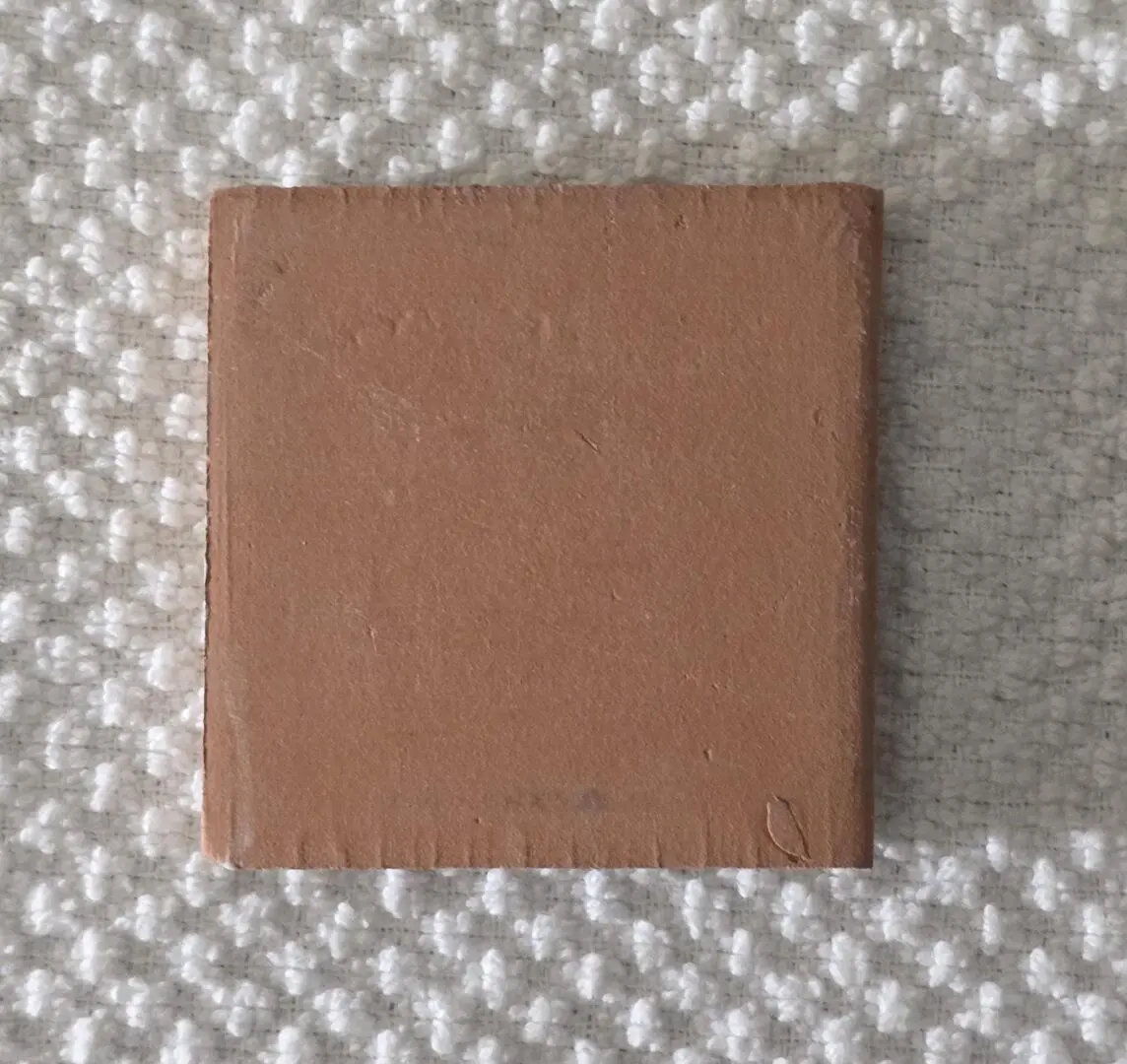 small terracotta ceramic tile on white fabric