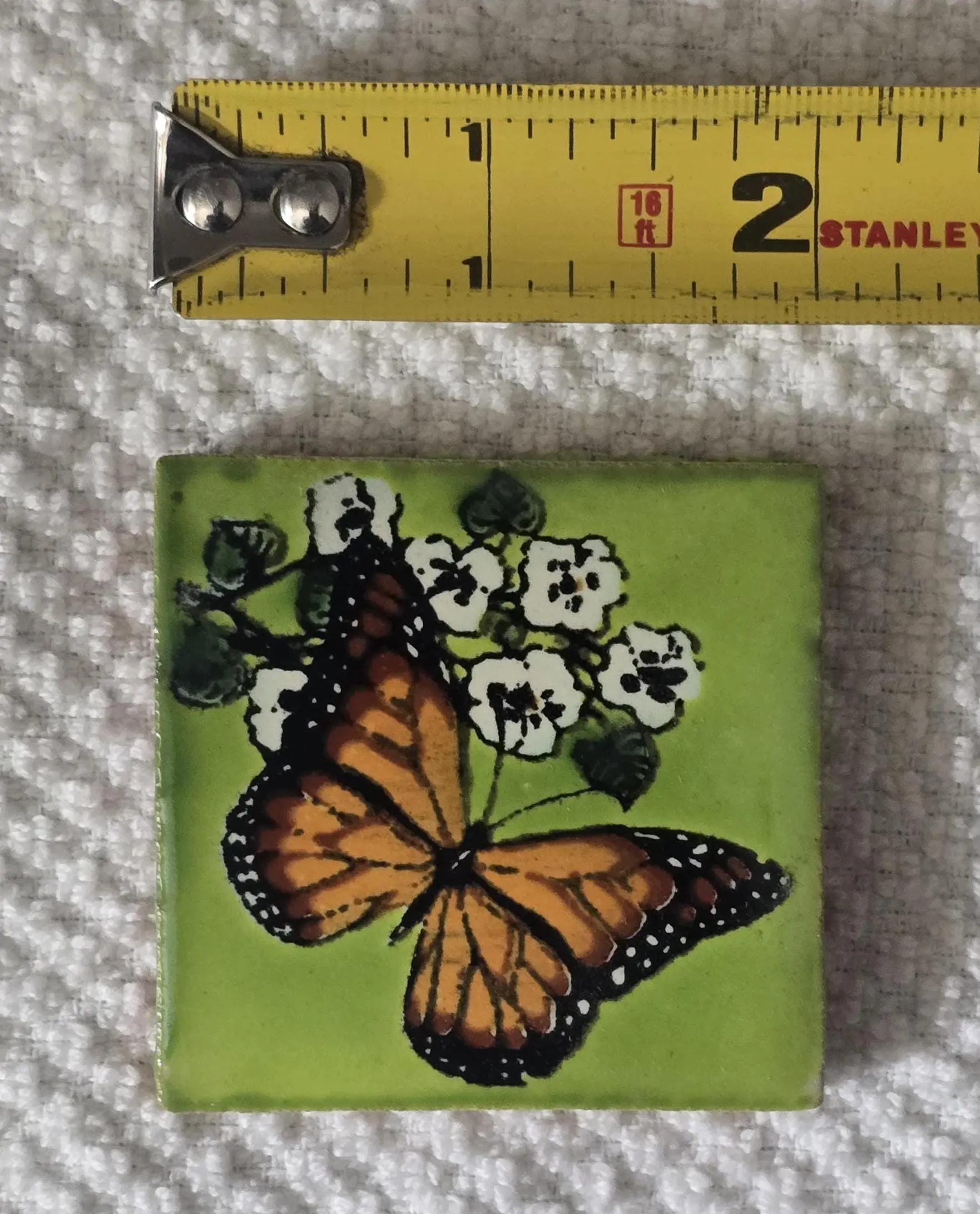 A monarch butterfly on white flowers on a green tile.
