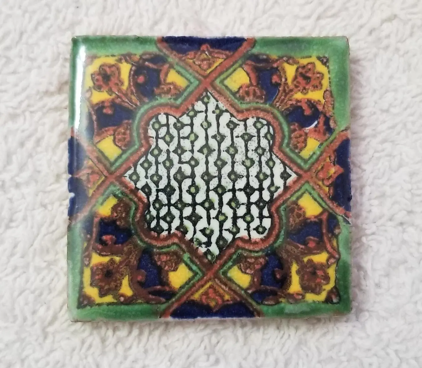 Small colorful ceramic tile with intricate geometric pattern