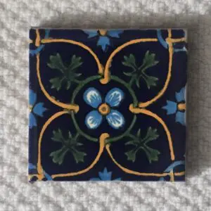 Decorative square tile with blue, green, and yellow floral pattern.