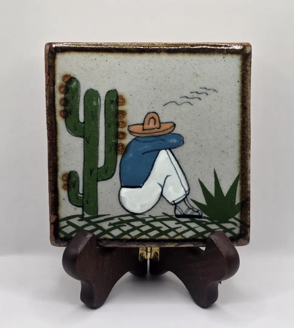 Hand-painted tile: seated man beside cactus