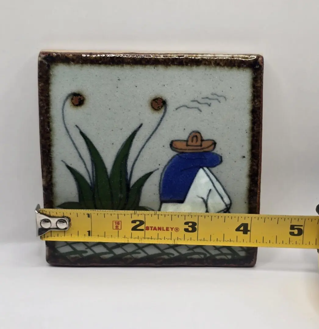 Tile with figure and plants, measuring tape.
