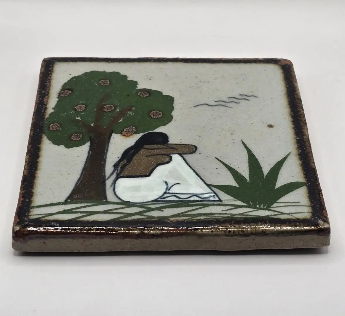 Woman sitting under tree on ceramic tile.