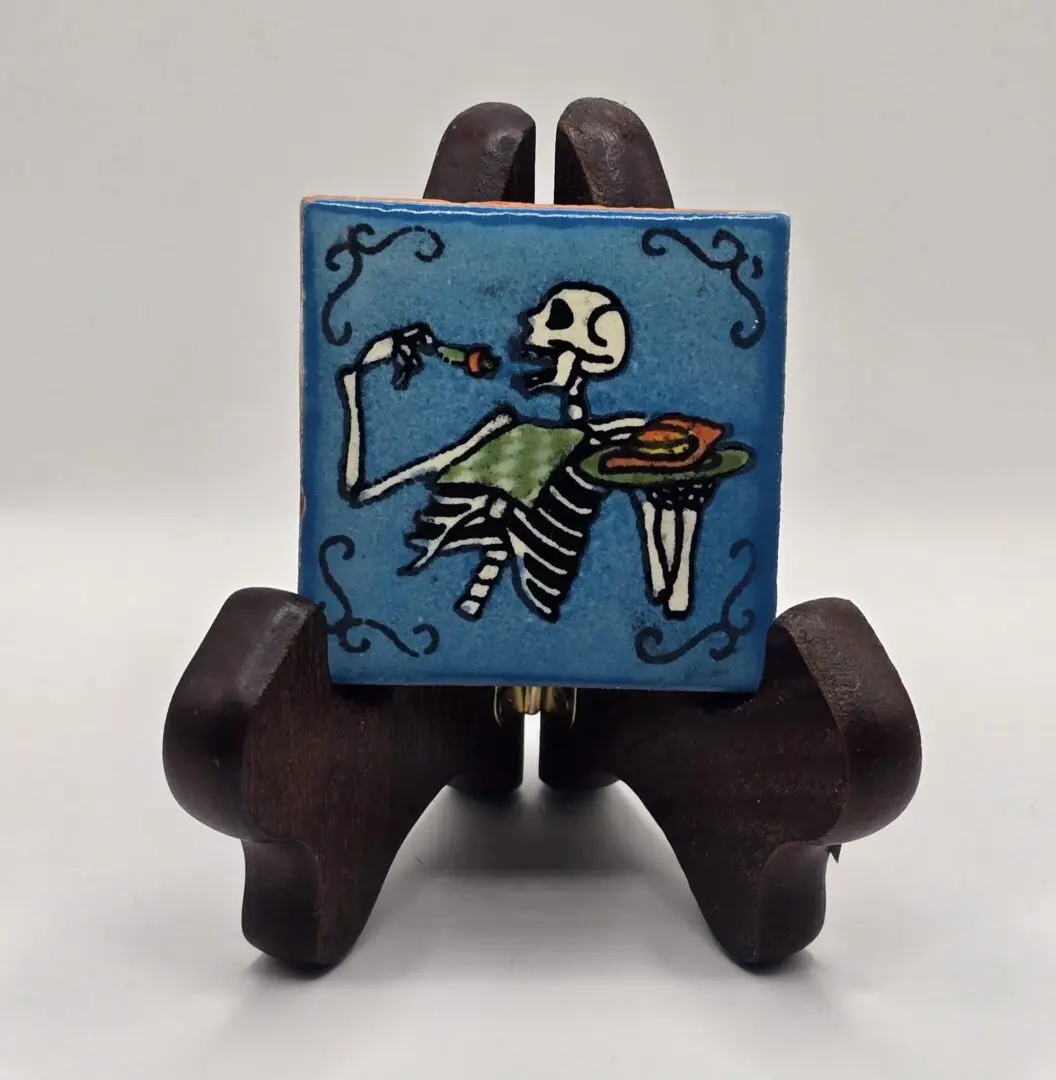 Skeleton eating on decorative ceramic tile.