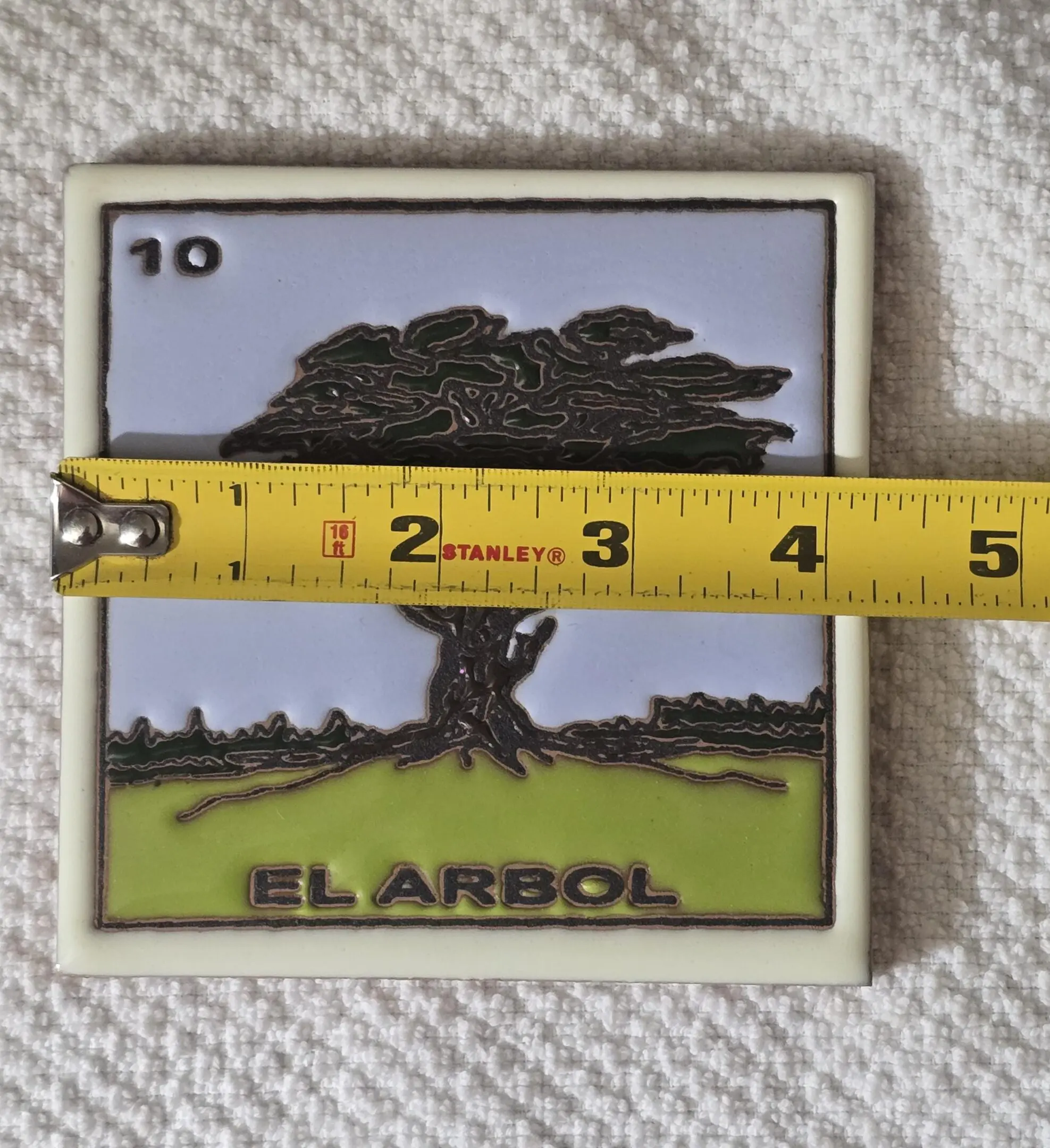 Tile with tree and measuring tape.