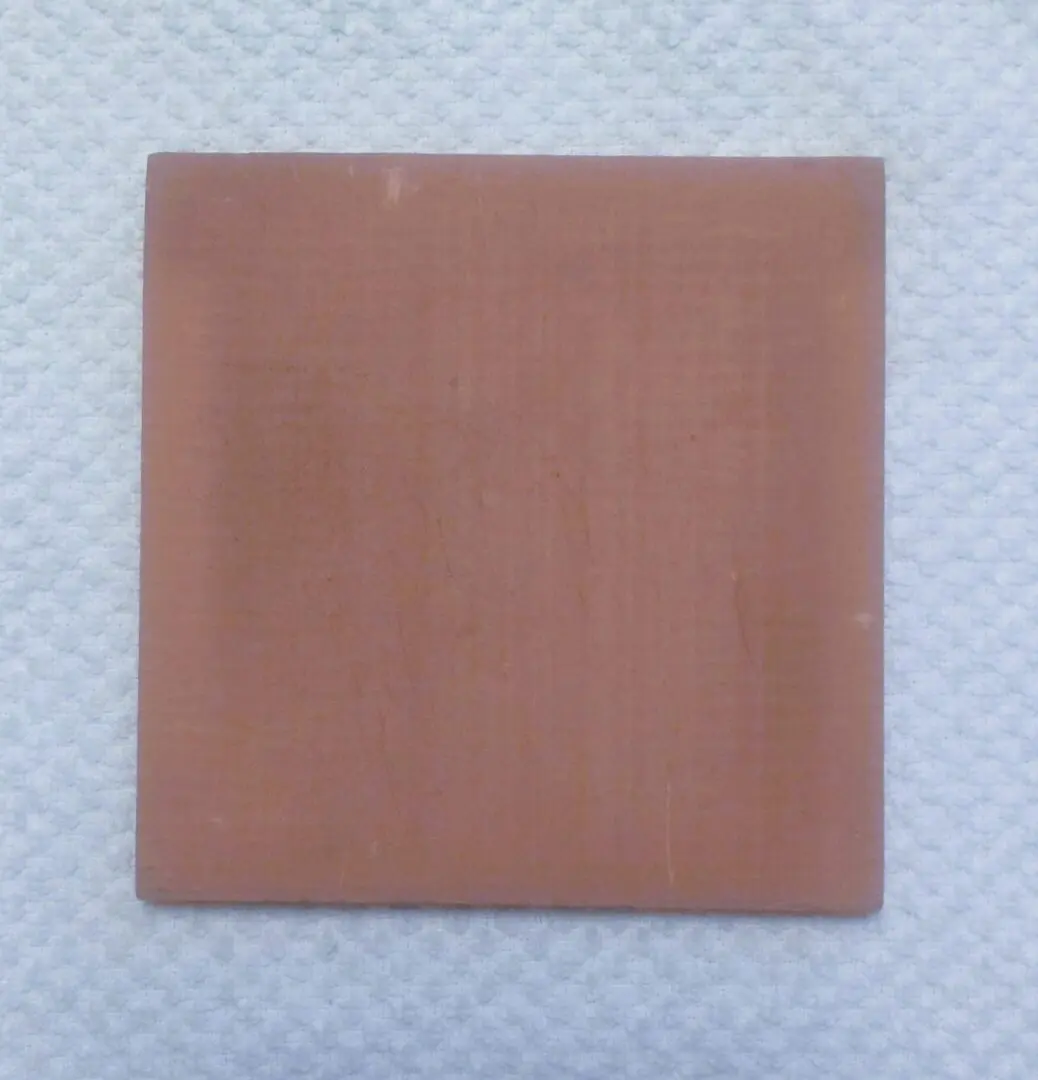 Square terracotta tile on white towel