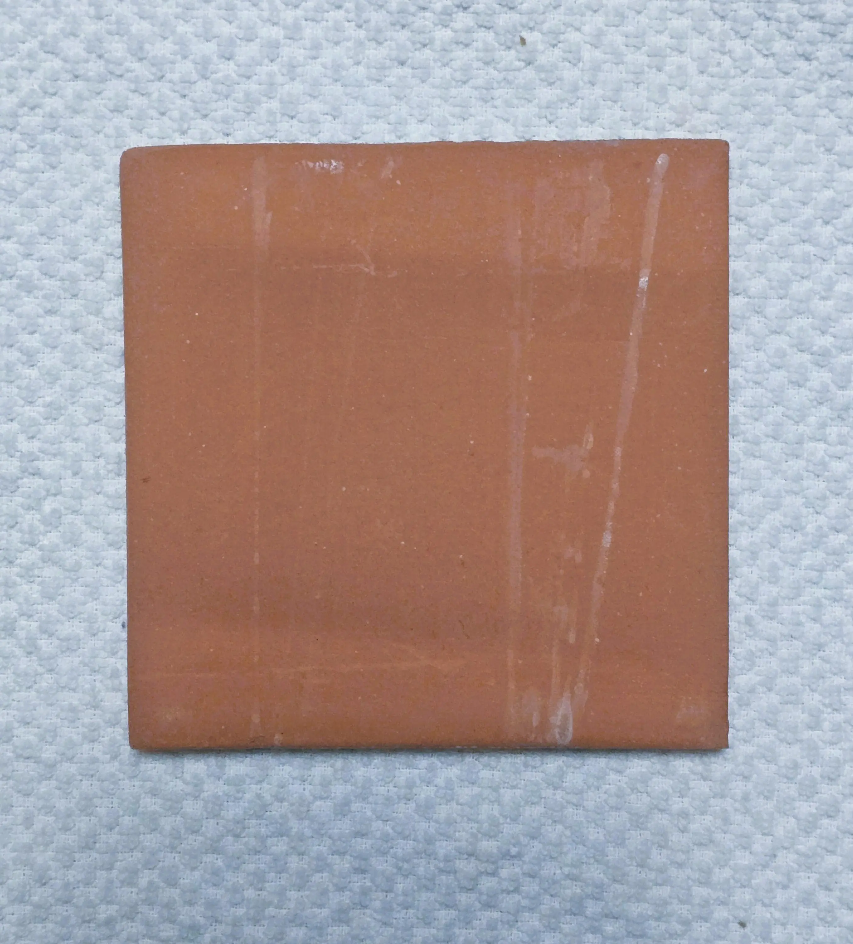 Terracotta tile on textured white surface.