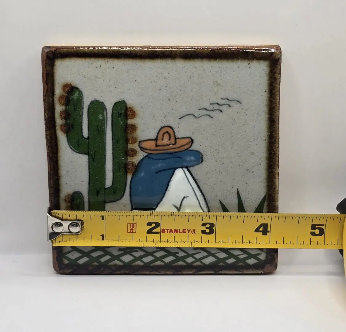 Decorative tile with cactus and figure.