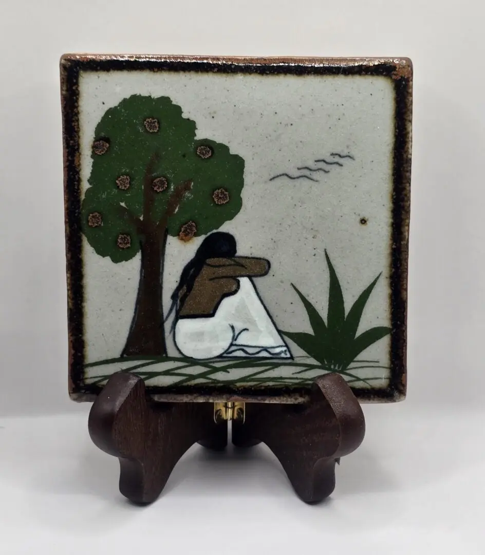 Tile art with figure under a tree.