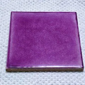 Purple ceramic tile on textured surface.