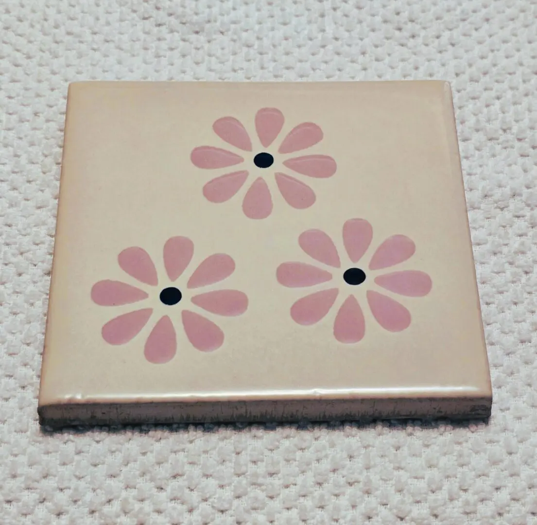 Square ceramic tile with three pink daisies