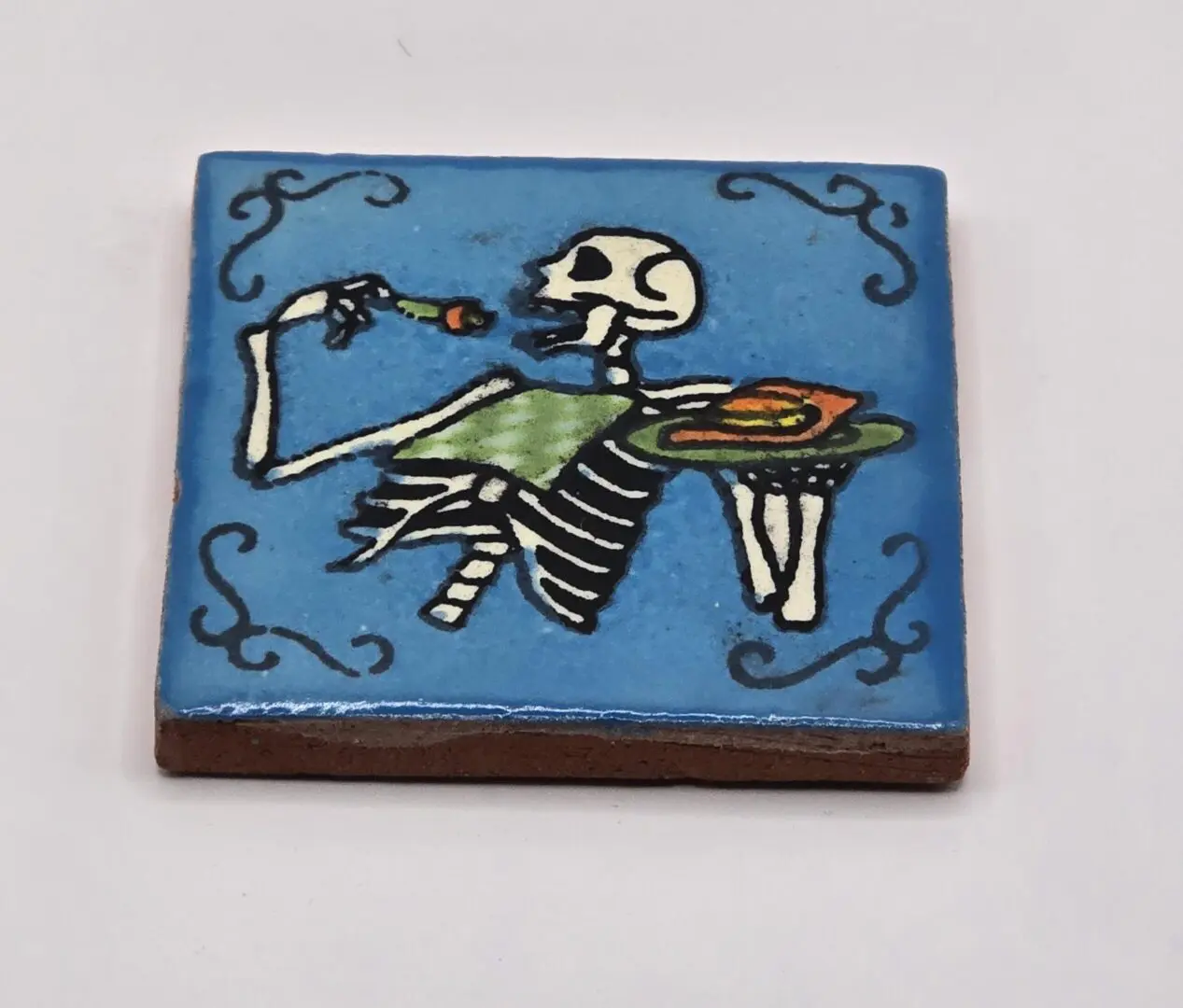 Skeleton eating with fork on blue tile.