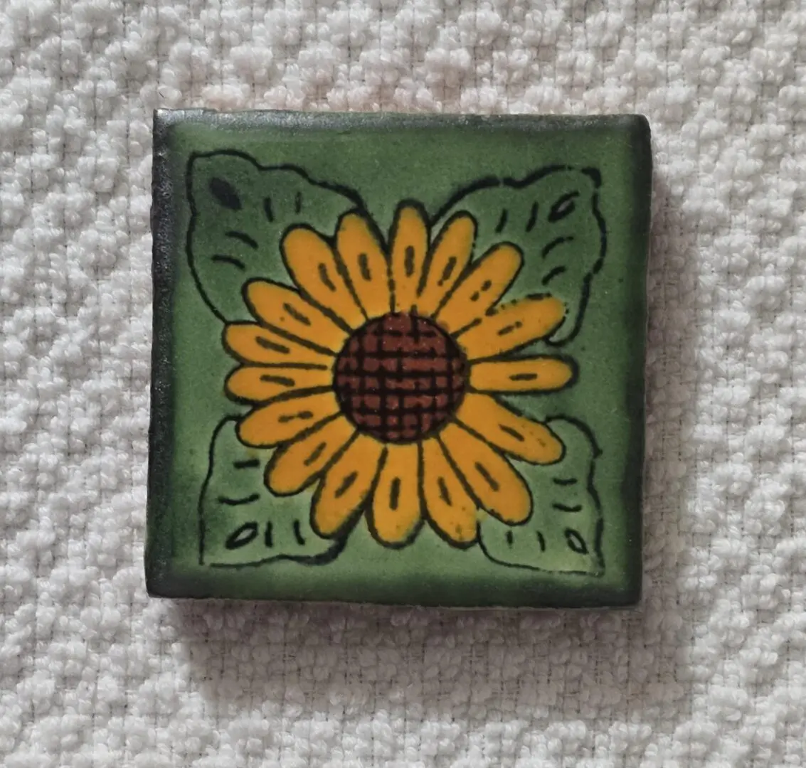Yellow sunflower on decorative green tile.
