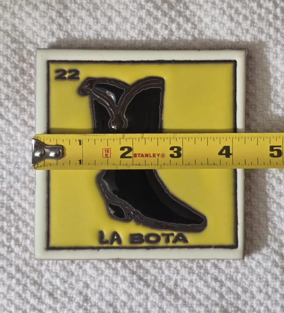 Yellow tile with boot design, measuring tape.