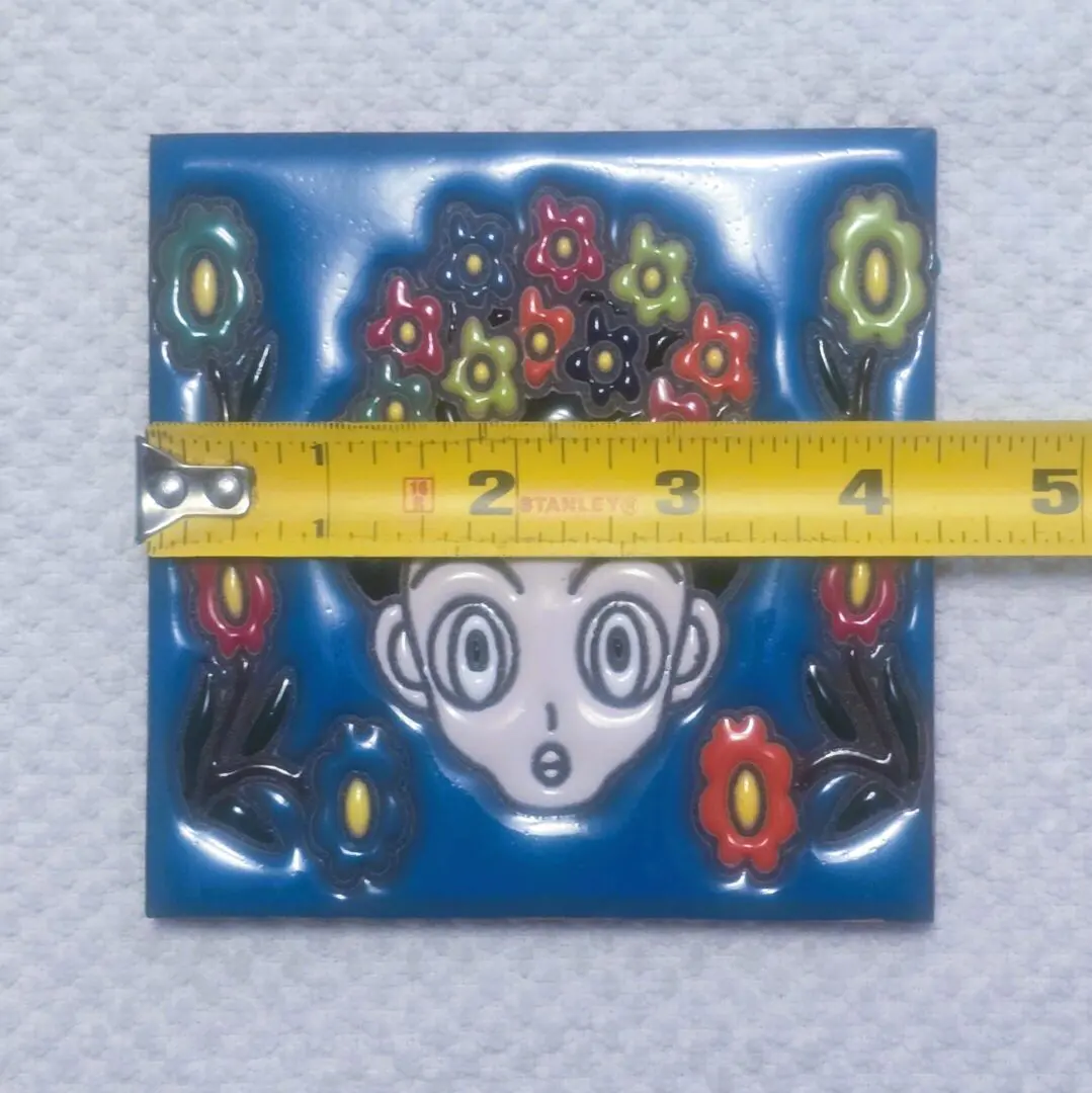 Blue ceramic tile with cartoon face, measuring tape
