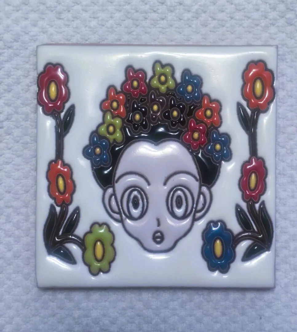 Cartoon face tile with colorful floral design.