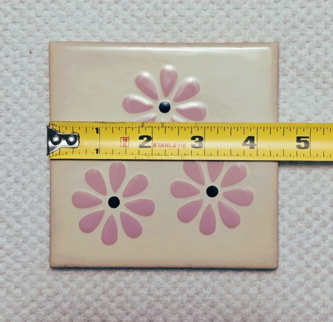Tile with pink flowers and measuring tape.
