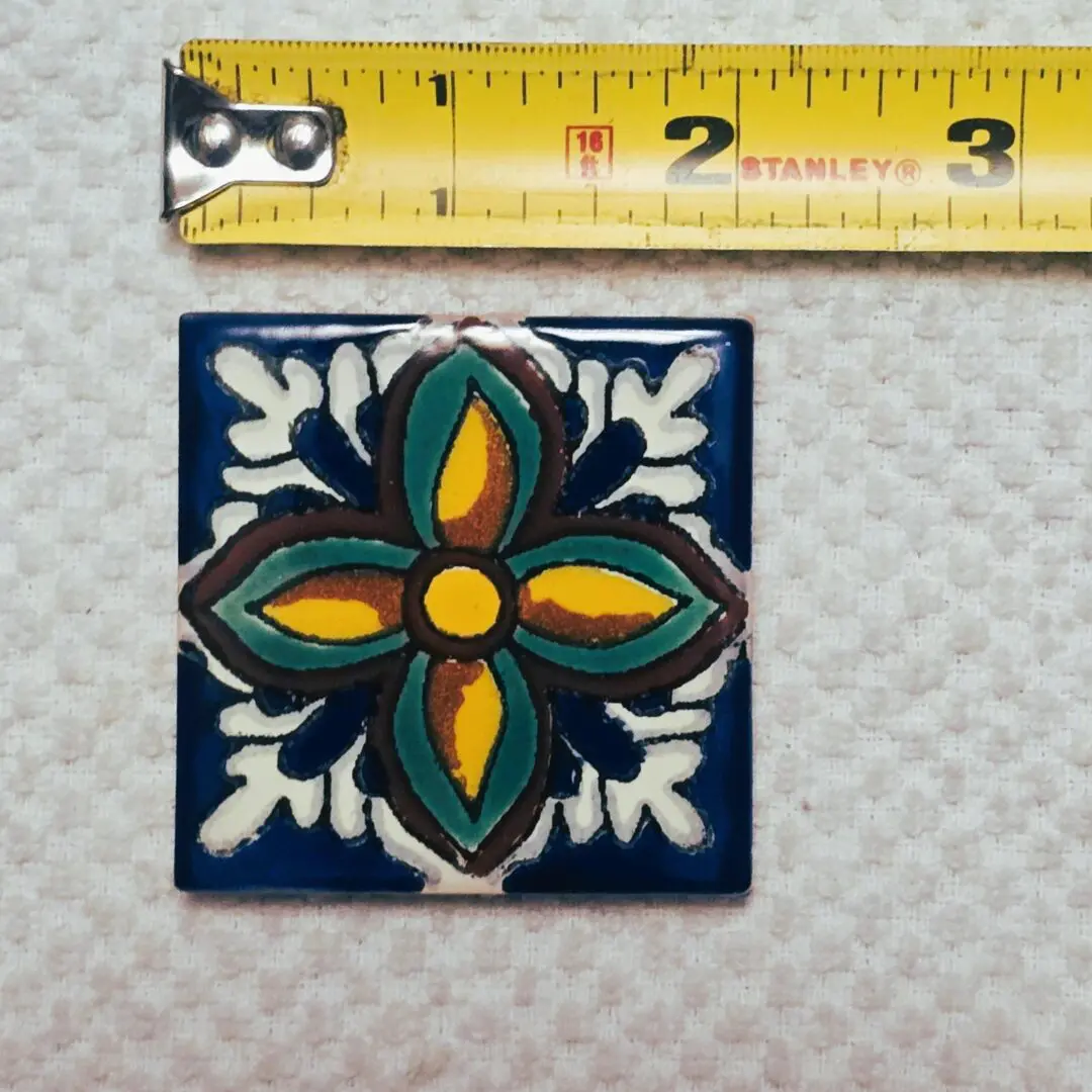 Decorative tile beside measuring tape.