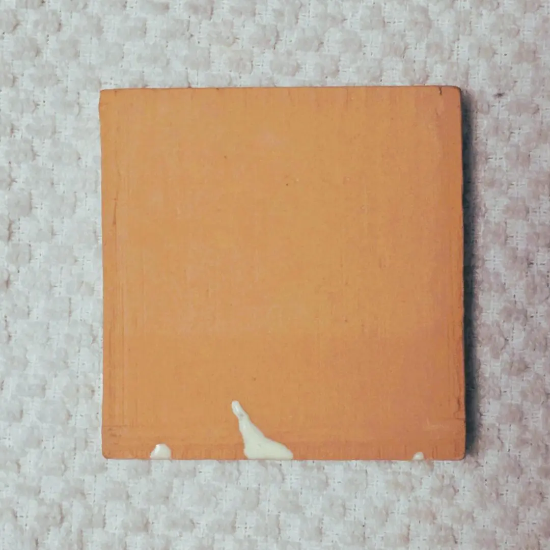 Orange square tile with white paint drips