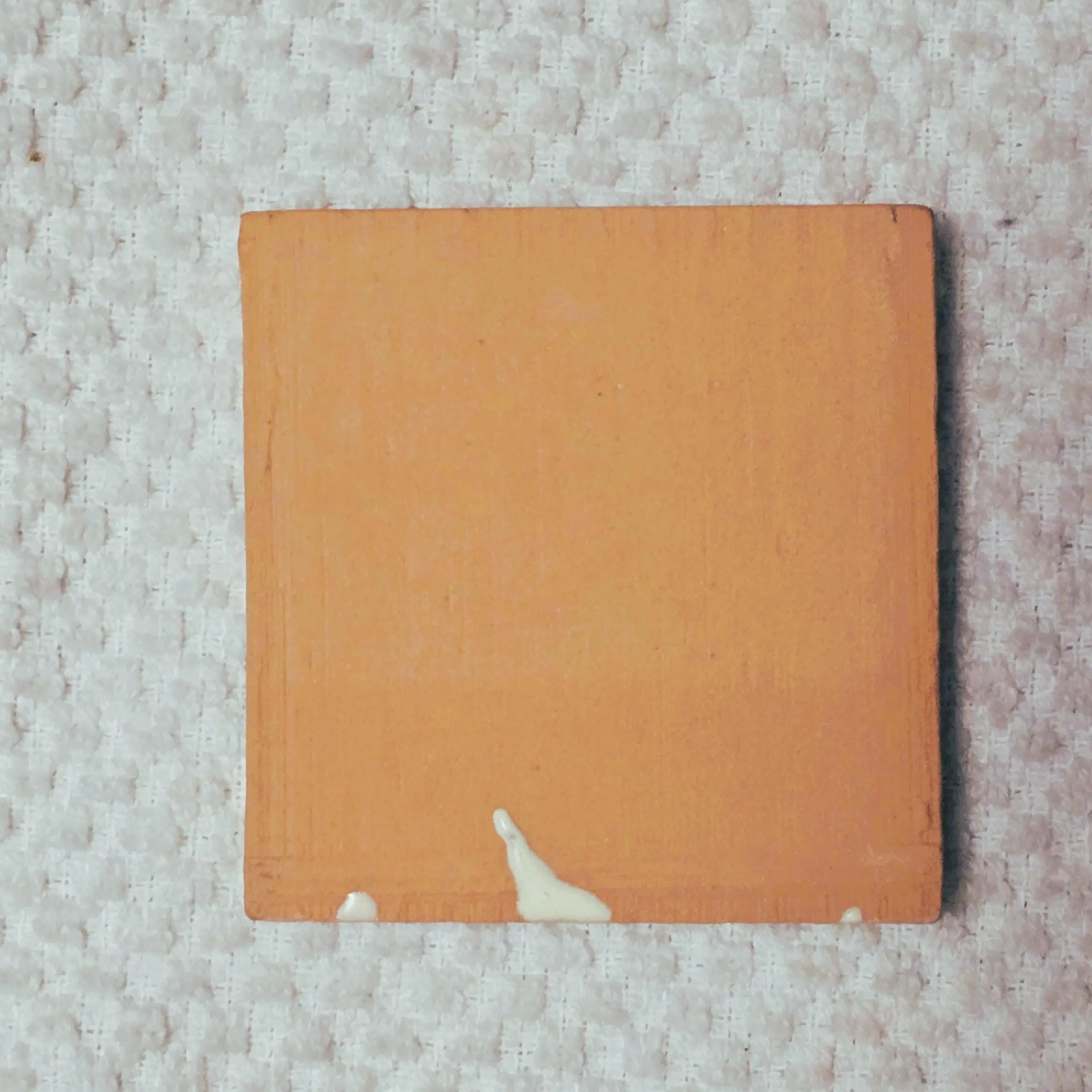 Square terracotta tile with white paint drips