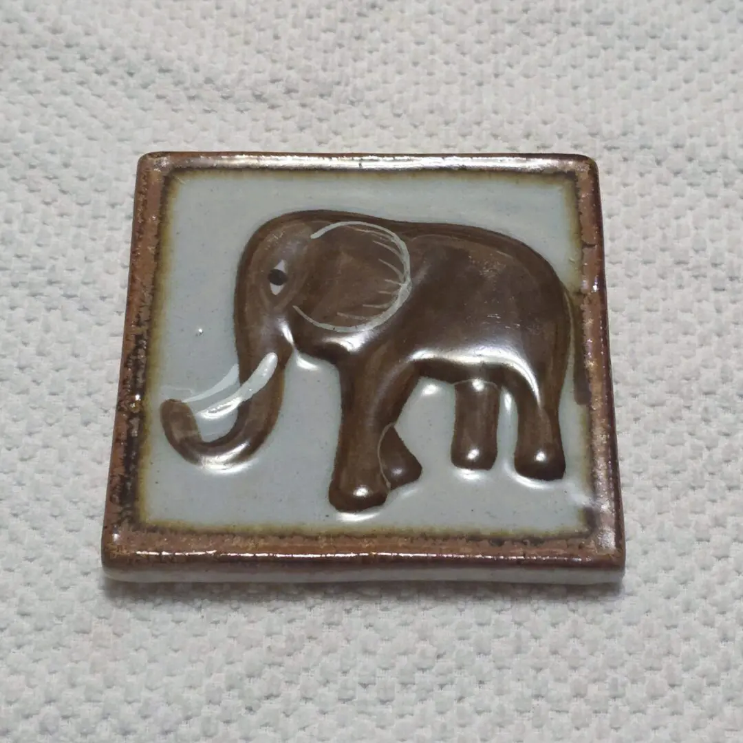 A small square tile with a simple elephant design.