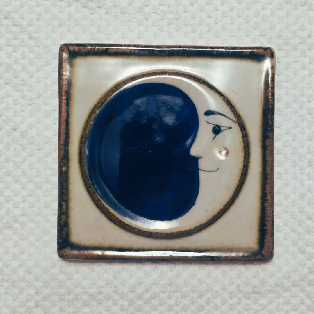 Ceramic tile with moon face design.