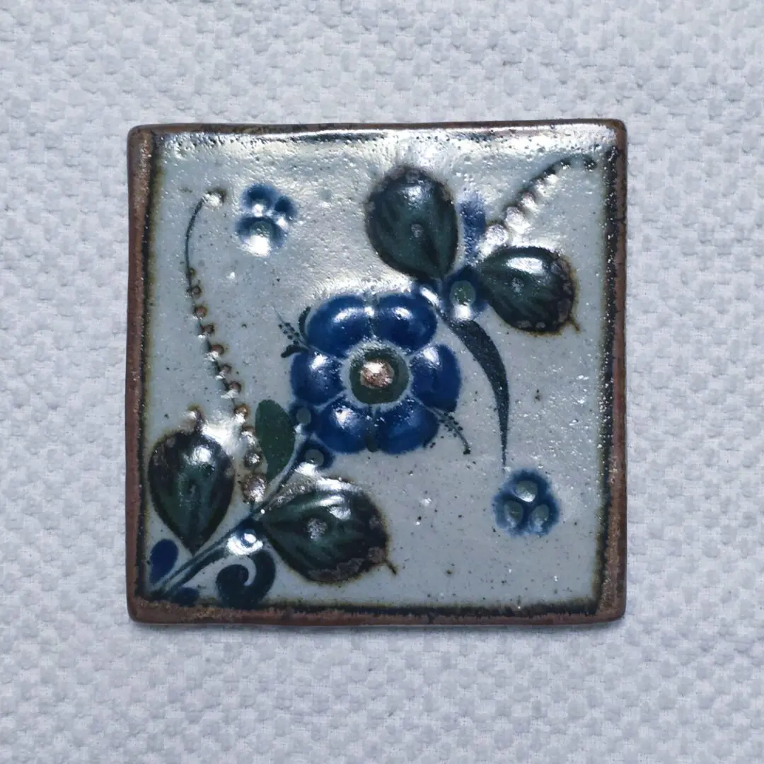 Square ceramic tile with blue floral design.