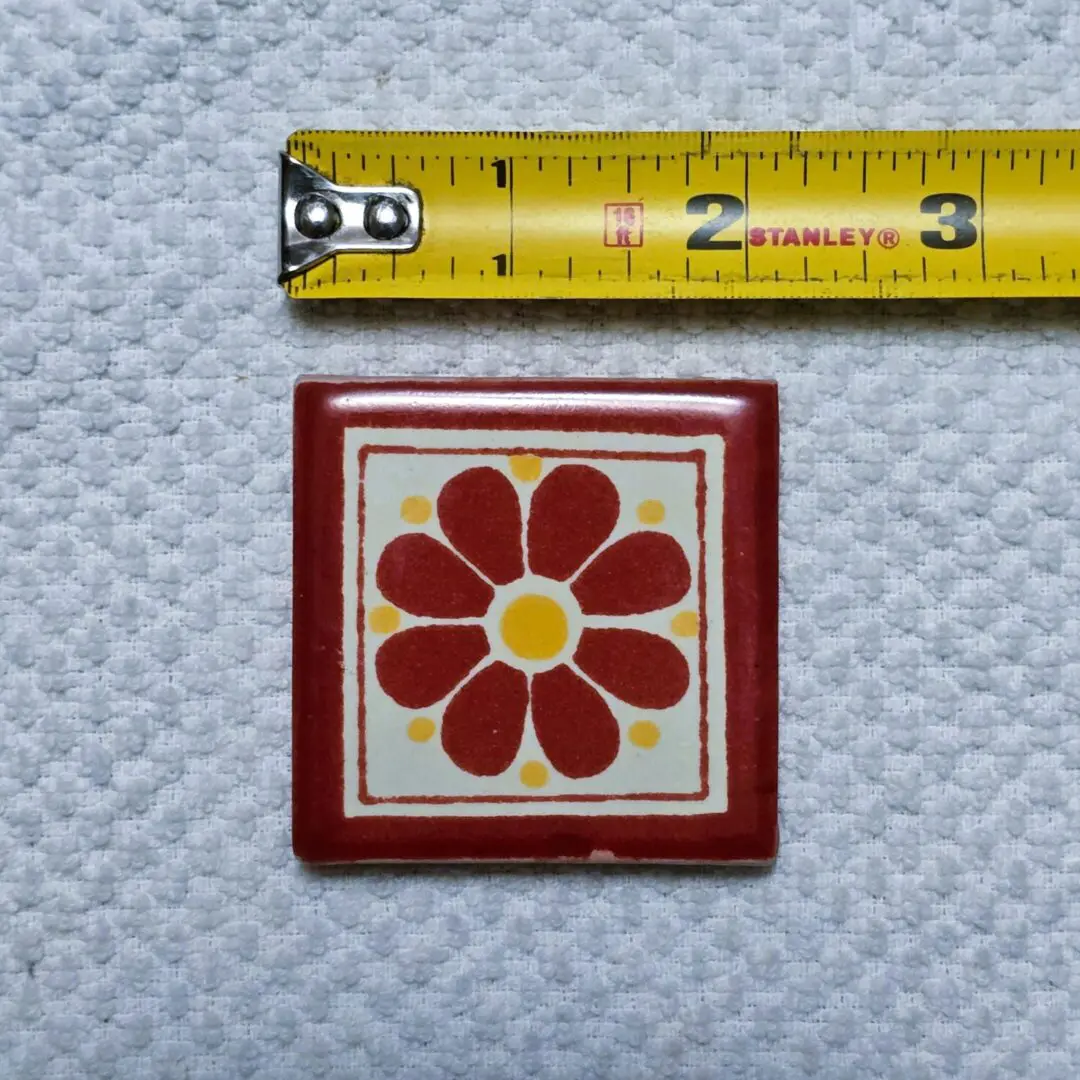 Tile with floral pattern beside measuring tape.