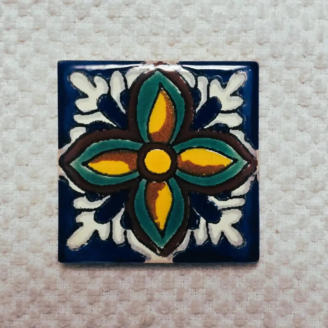 Colorful floral ceramic tile on textured background.