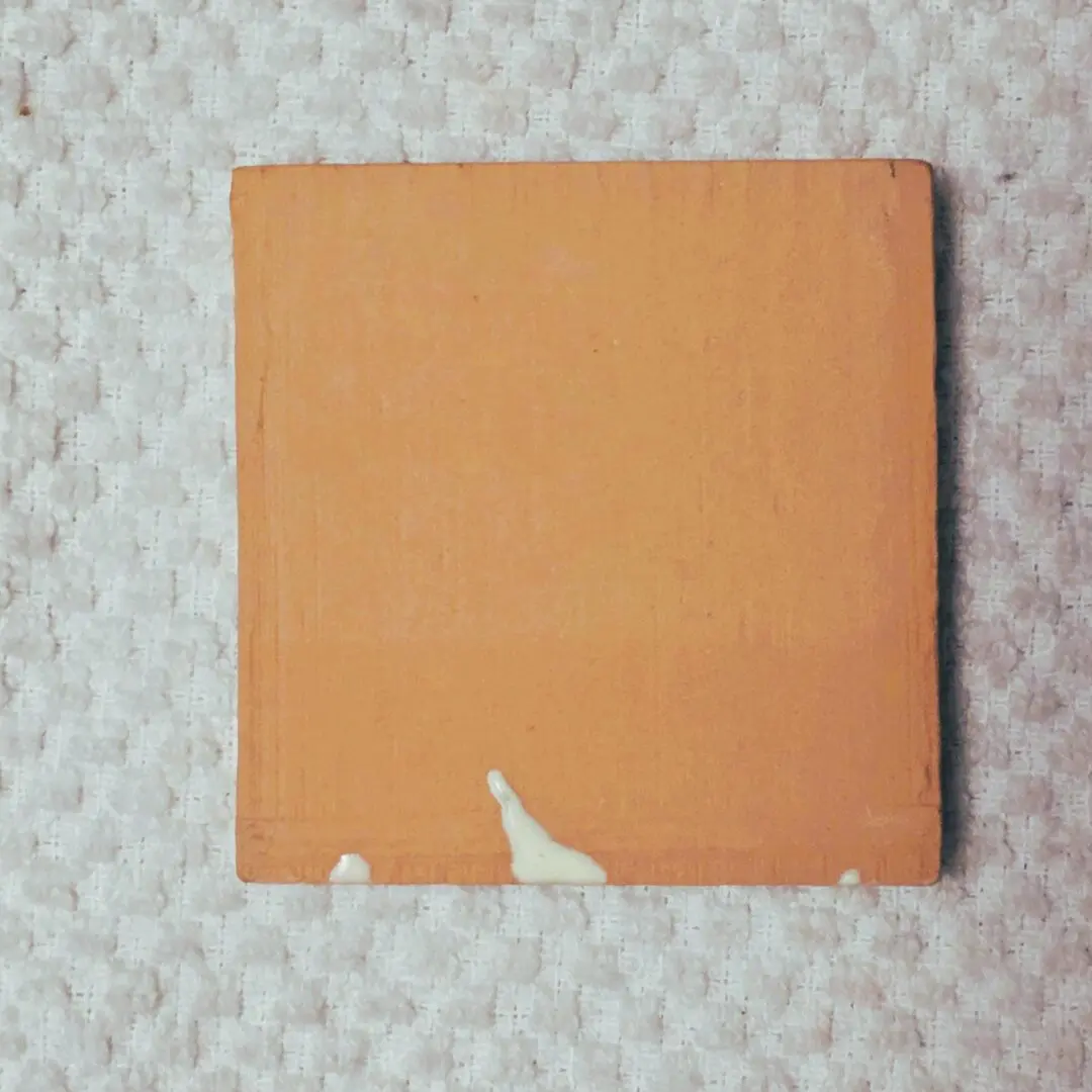 Orange tile on textured white background.