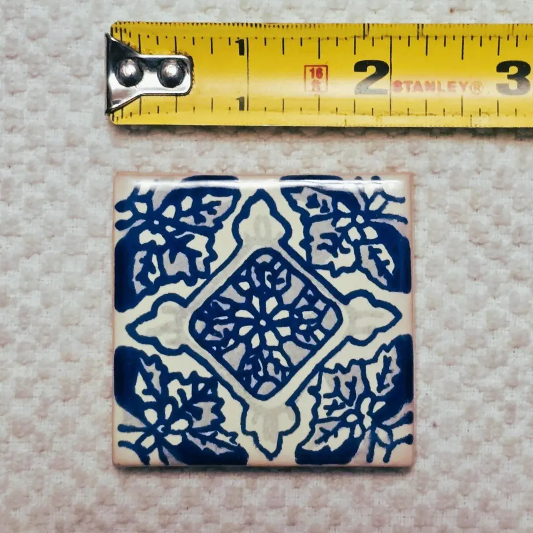 Blue patterned tile with measuring tape above.