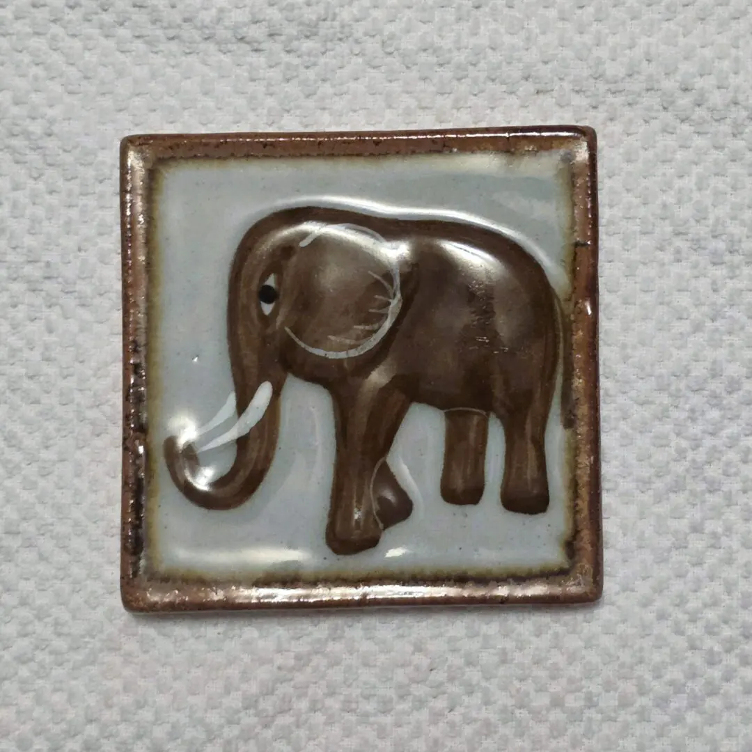 A ceramic tile with a raised elephant design.