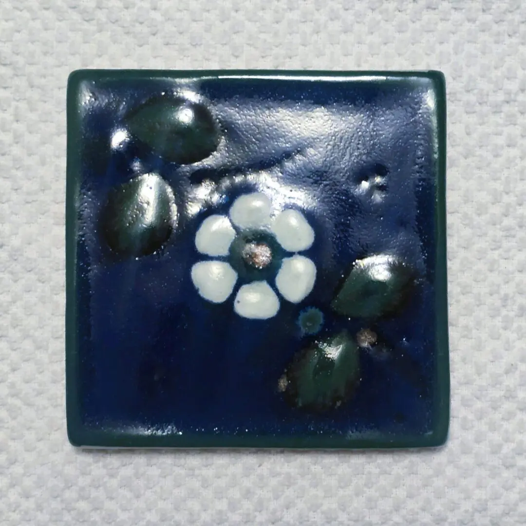 Blue ceramic tile with white flower design.
