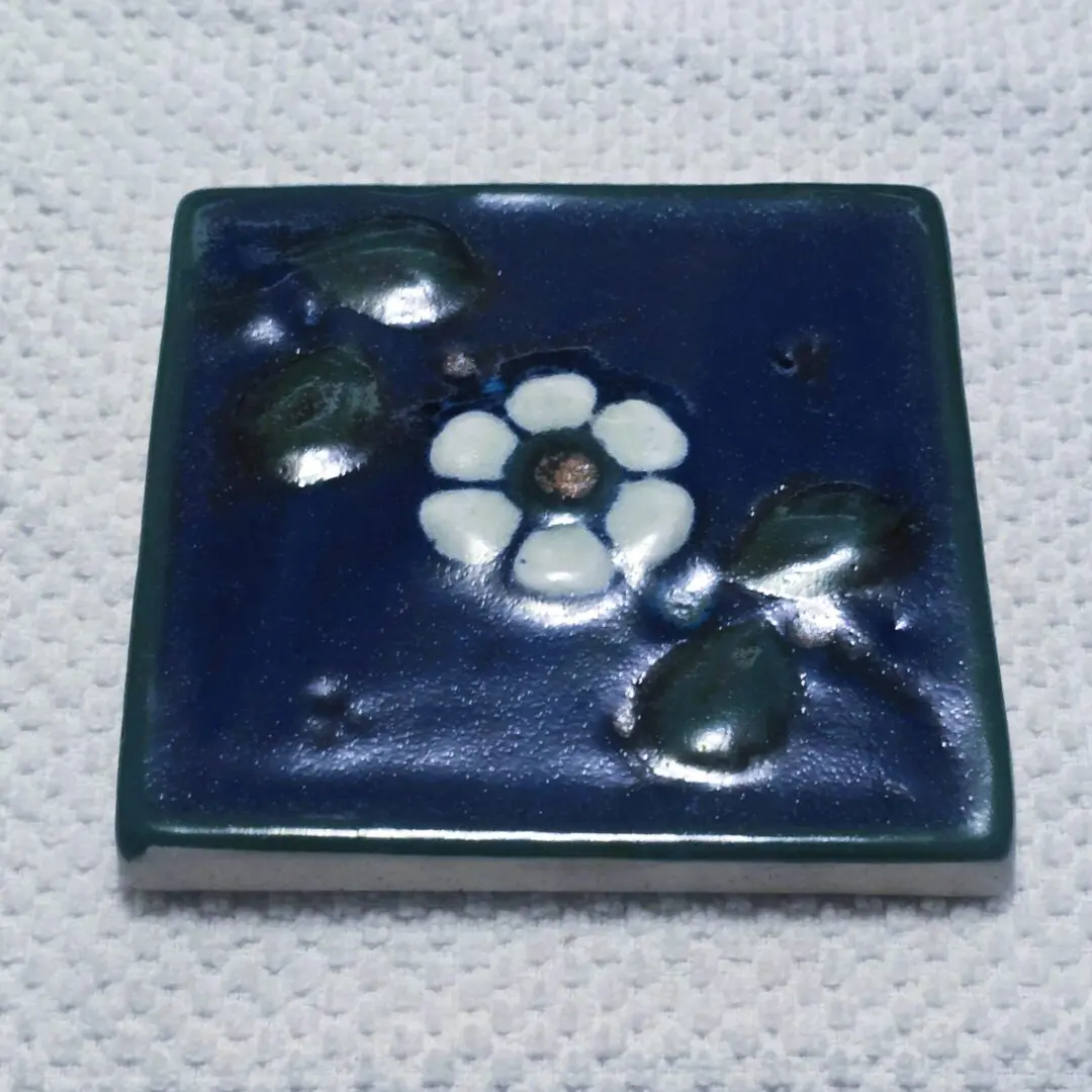 Square ceramic tile with floral design.