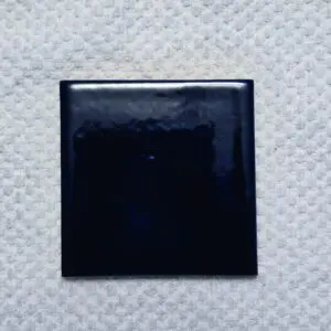 Glossy navy ceramic tile on textured white background