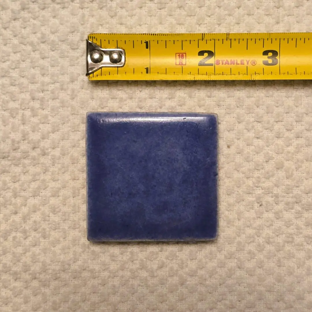 Blue square tile with measuring tape above.