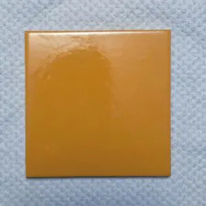 A single orange square tile on a textured white surface.