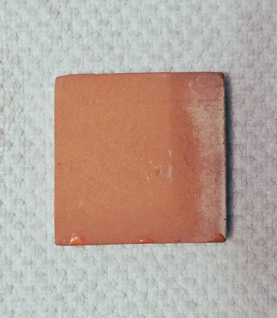 Square terracotta ceramic tile on textured fabric
