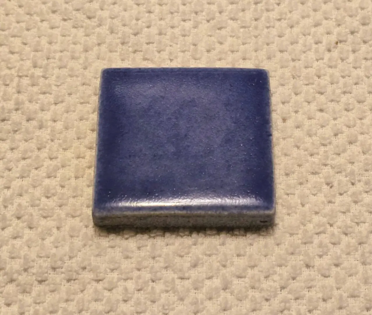 Glazed blue square ceramic tile on beige