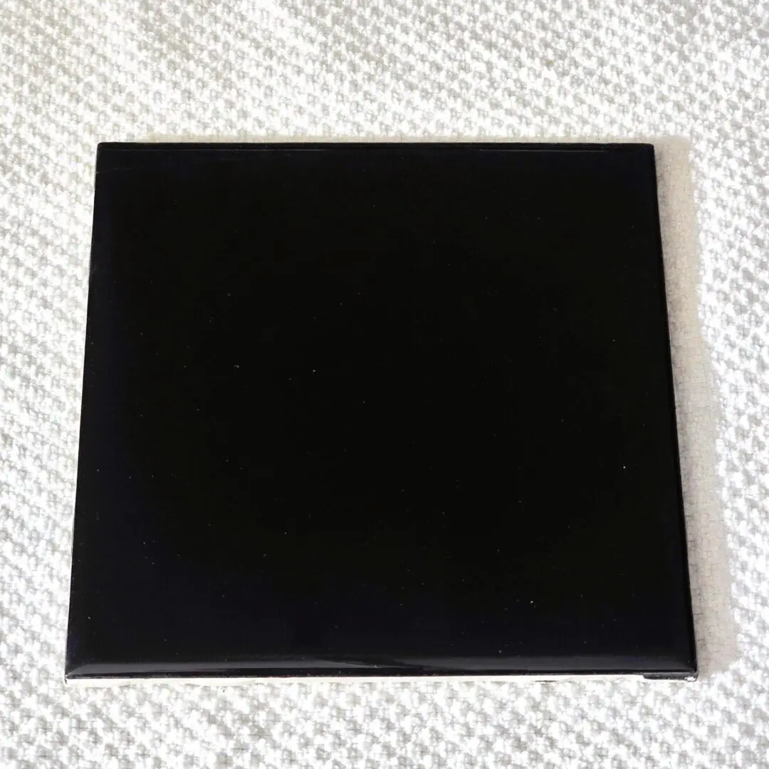 Glossy black square tile on textured surface